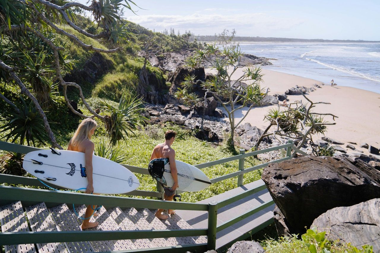couple taking surf boards down to Cabarita Beach