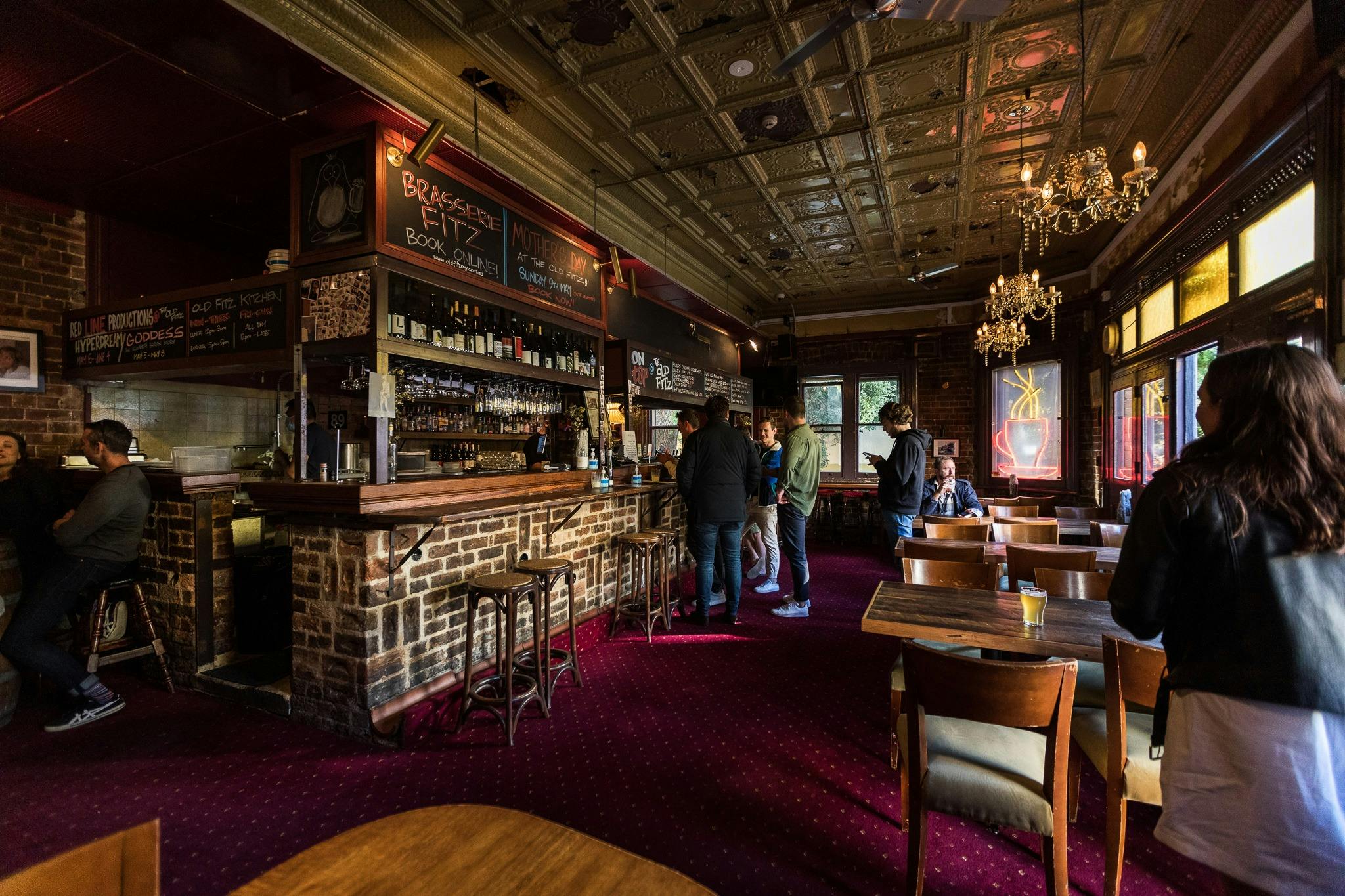 People lining up at a bar with rustic features.